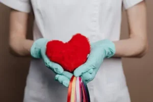 A nurse holding a red heart in their hands.
