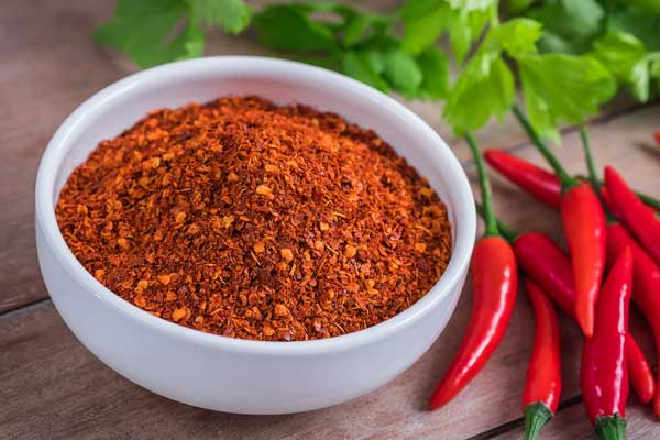 Cayenne chili peppers and grounded cayenne pepper in a bowl